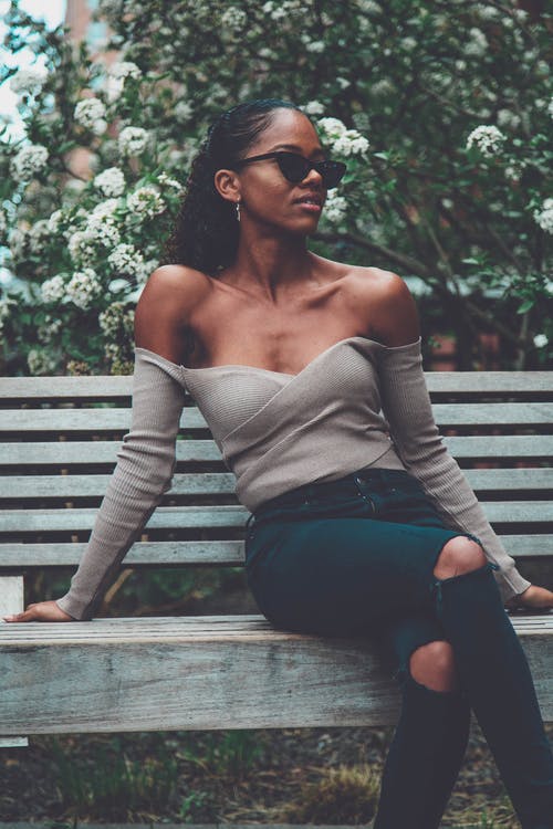 女人坐在植物旁的长椅上 · 免费素材图片