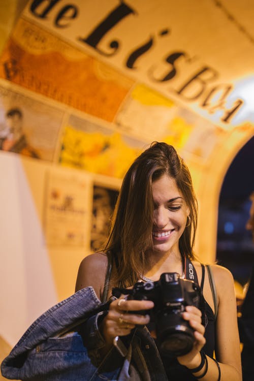 女人微笑着拿着单反相机的选择性聚焦摄影 · 免费素材图片
