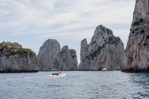 海上航行与灰色山脉包围的船 · 免费素材图片