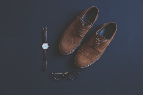 眼镜和手表旁边的棕色皮革方鞋 · 免费素材图片