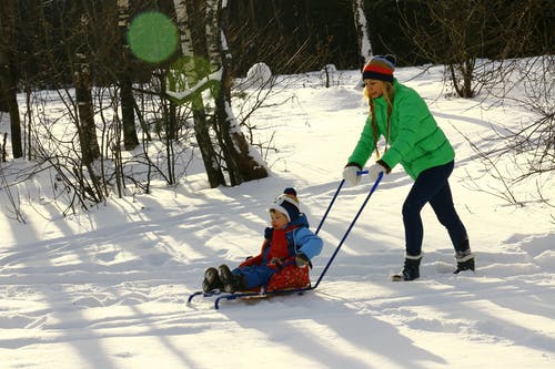 女人在雪橇上推蹒跚学步 · 免费素材图片