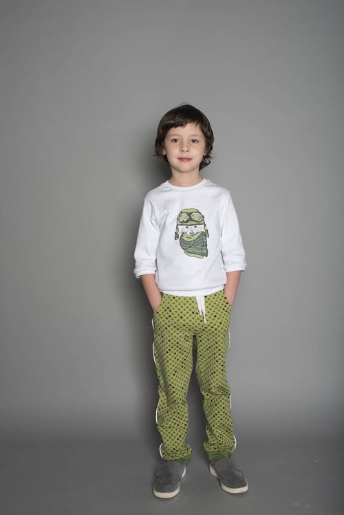 男孩穿着白色和绿色的t恤和绿色的裤子 · 免费素材图片