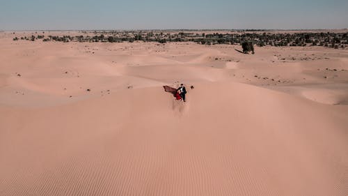 女人和男人坐在沙漠上 · 免费素材图片