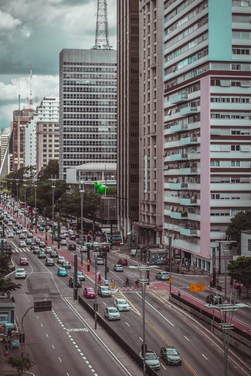 高层建筑附近道路上的各种颜色的车辆 · 免费素材图片