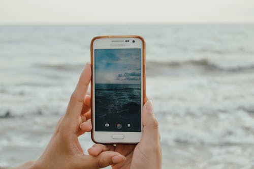 拿着智能手机捕捉海浪的人 · 免费素材图片