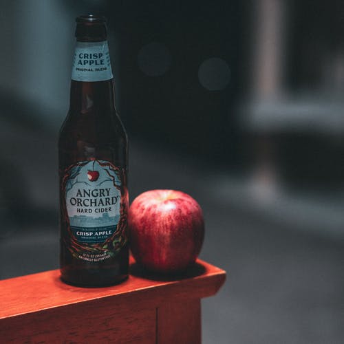 红苹果果旁边的愤怒果园硬苹果酒瓶 · 免费素材图片