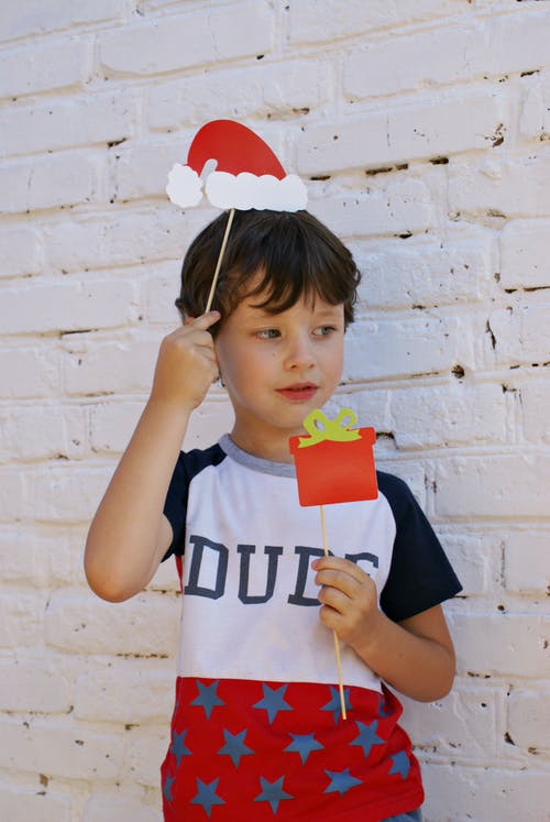 一个男孩抱着红色圣诞贺卡的照片 · 免费素材图片
