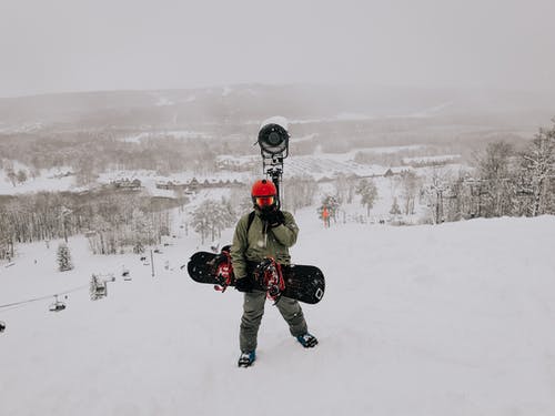 拿着滑雪板的人佩带的工作服站立在雪原 · 免费素材图片