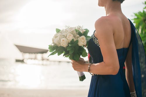女人穿着蓝色的连衣裙，拿着白色的花瓣花束 · 免费素材图片