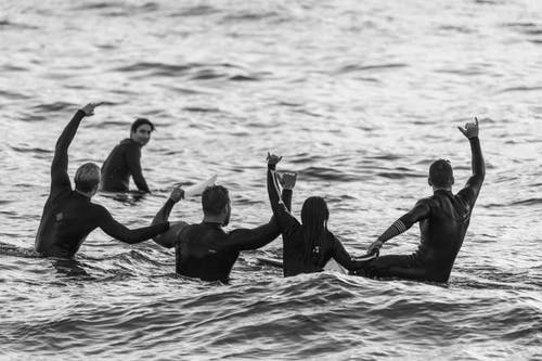 五个冲浪者在海上玩乐 · 免费素材图片