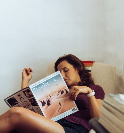 读杂志在房间里时躺在床上的女人 · 免费素材图片