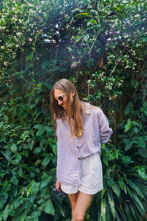 紫色顶部站在绿色的植物附近的女人 · 免费素材图片