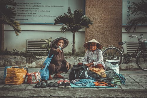 两个女人坐在人行道上 · 免费素材图片