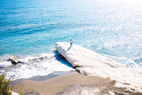 站在水附近的白色巨石上的人 · 免费素材图片