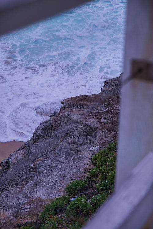 海滩波浪旁边的灰色岩石峭壁 · 免费素材图片