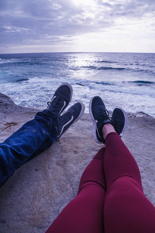 坐在悬崖附近海洋上的人的照片 · 免费素材图片