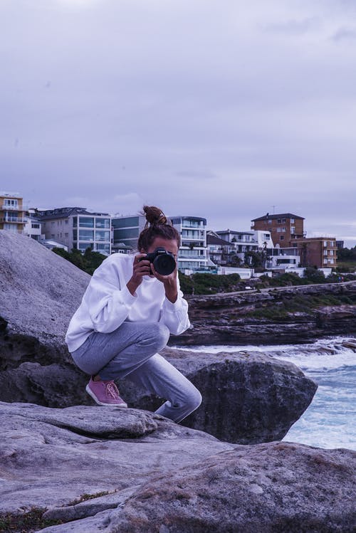 拍照片时坐在岩石上的女人 · 免费素材图片
