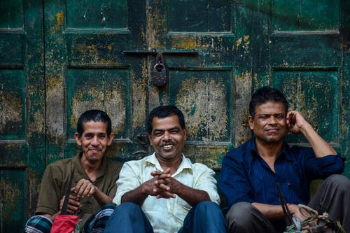 三名男子坐在门边微笑 · 免费素材图片