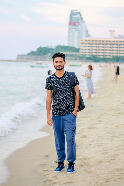 站在海滩上的男人微笑着 · 免费素材图片