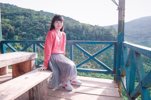 坐在长凳上的粉红色毛衣的妇女 · 免费素材图片