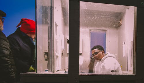 男子坐在玻璃墙前的椅子上 · 免费素材图片