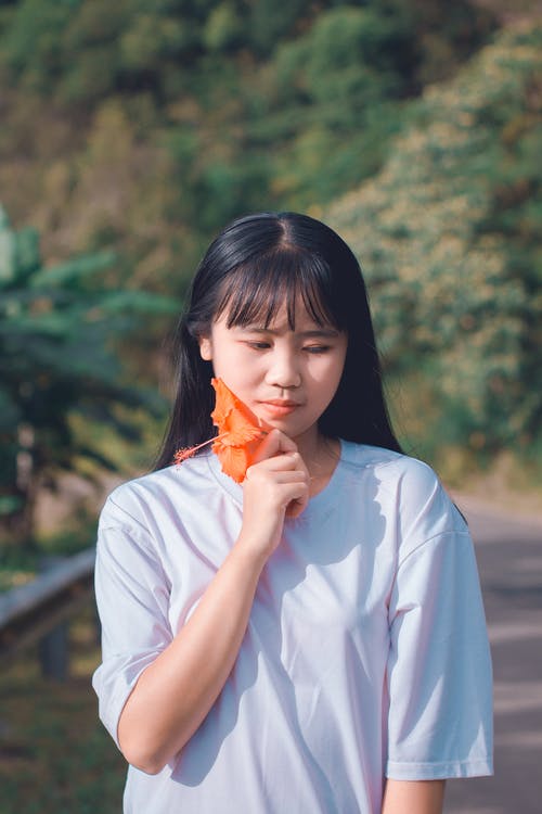 女人抱着橙色芙蓉花 · 免费素材图片