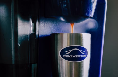 不锈钢杯装满咖啡的咖啡机 · 免费素材图片