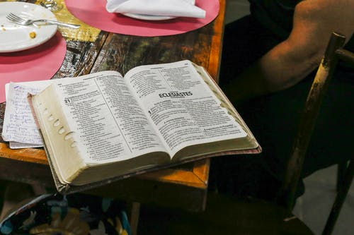 打开的圣经书在棕色的桌子上的照片 · 免费素材图片