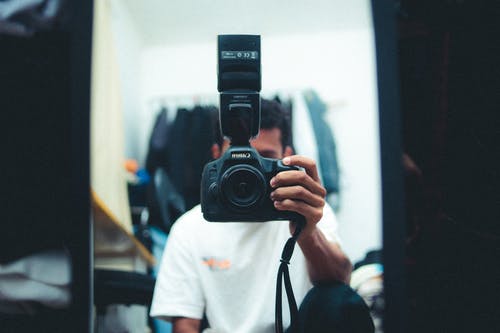 男子手持黑色相机 · 免费素材图片