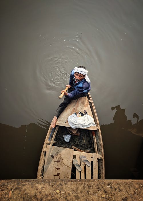 男子站在船上时，按住杆 · 免费素材图片