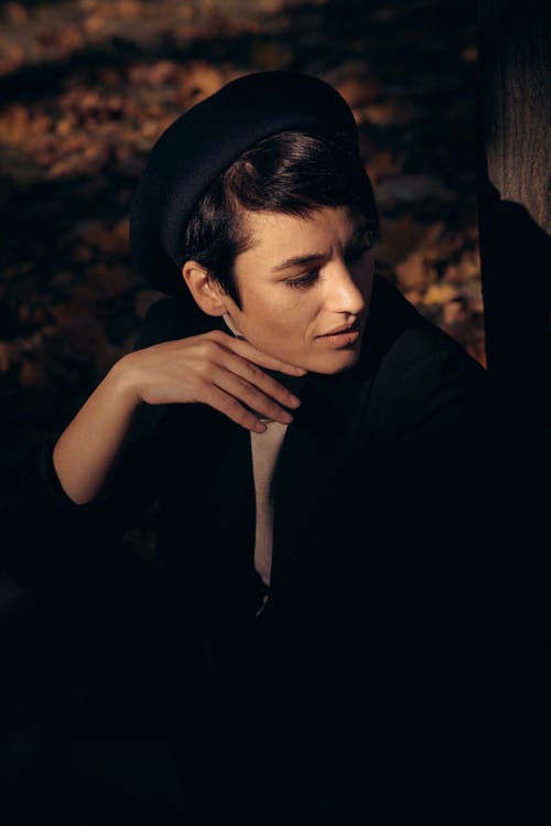 女人坐在地上，用手在下巴上向右看 · 免费素材图片