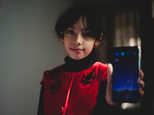 女孩穿着红色和黑色的顶部拿着智能手机 · 免费素材图片