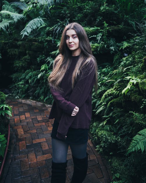 女人站在植物之间的通路上的照片 · 免费素材图片