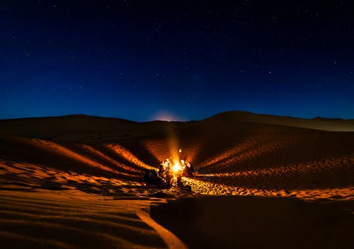 晚上在沙漠上有篝火的人 · 免费素材图片