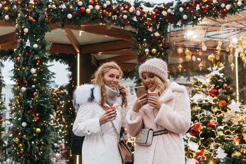 两个女人在圣诞节装饰品附近 · 免费素材图片