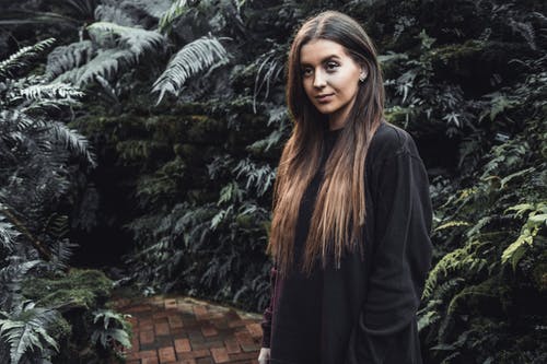 女人站在被植物包围的通路上 · 免费素材图片