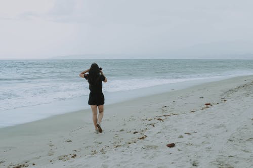 在白色的沙滩上行走的女人 · 免费素材图片