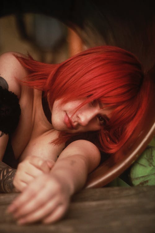 躺在褐色的表面上的红发女人 · 免费素材图片