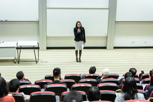 拿着话筒的妇女站立在人群前面 · 免费素材图片