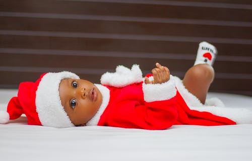 婴儿躺在床上时穿着圣诞老人服装 · 免费素材图片