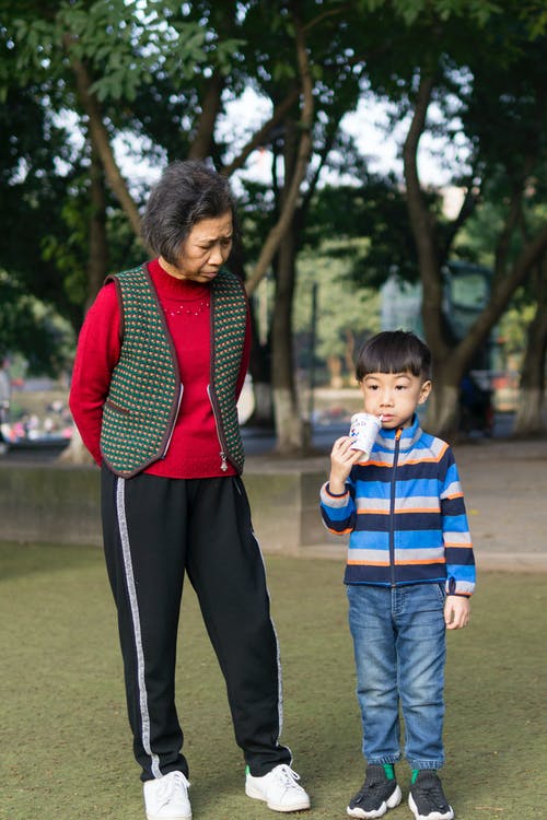 蹒跚学步的男孩站在女人旁边 · 免费素材图片