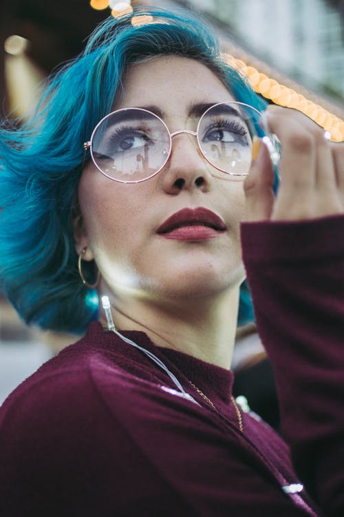 女人在紫色上衣与持有字符串灯的蓝色头发的特写照片 · 免费素材图片
