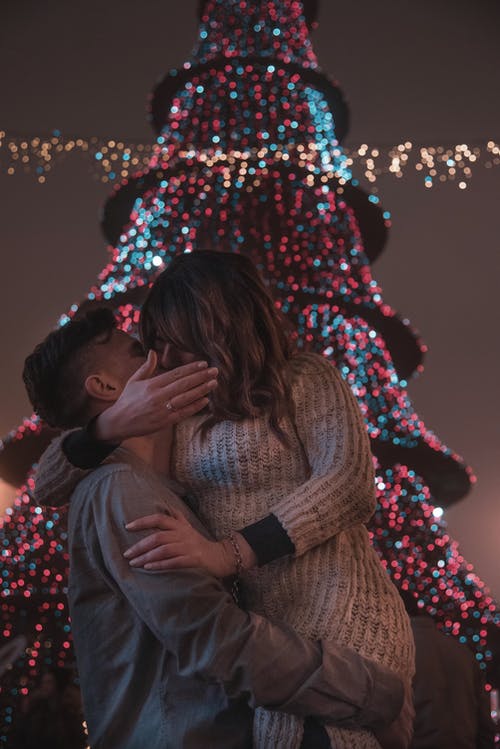 情侣接吻在圣诞树前的照片 · 免费素材图片