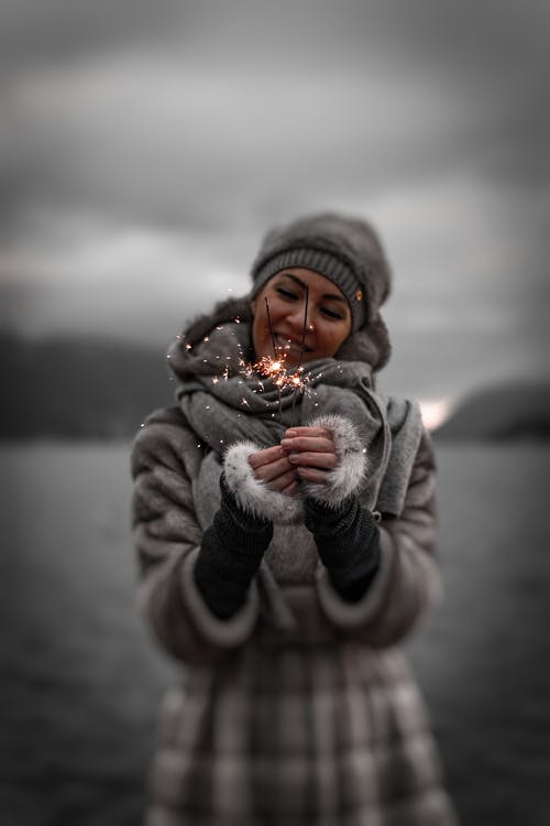 微笑的女人，拿着点燃的烟火的照片 · 免费素材图片