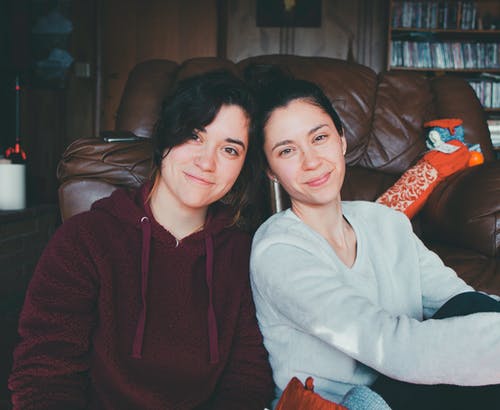 两个女人坐在沙发上的地板上 · 免费素材图片