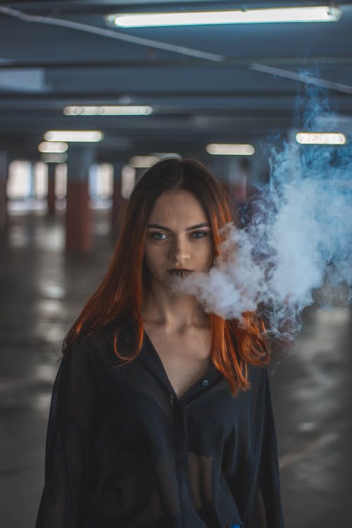 在停车场上吸烟的女人 · 免费素材图片