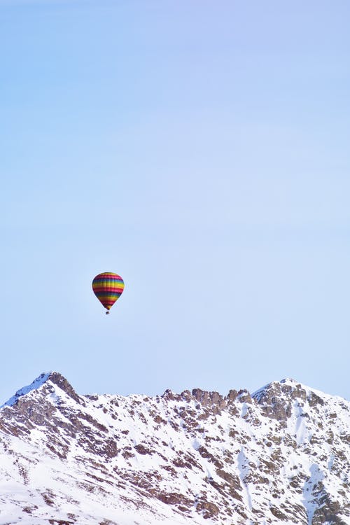 在白雪皑皑的高山上空飞行的热气球 · 免费素材图片