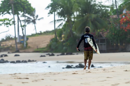 在海边散步时携带冲浪板的人 · 免费素材图片