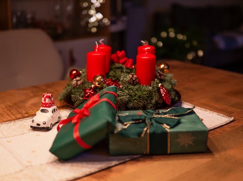 绿色礼品盒旁边桌上未点燃的红色到来蜡烛 · 免费素材图片