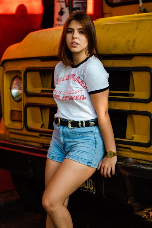 女人站在反对黄色卡车 · 免费素材图片